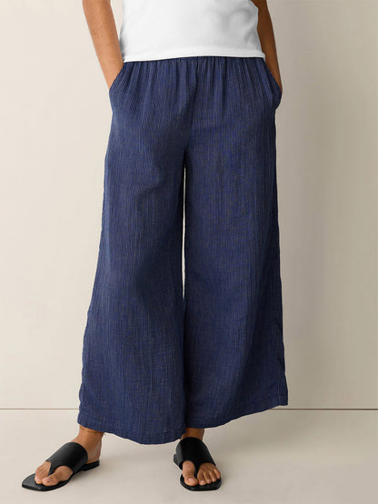 Person wearing Eileen Fisher Striped Organic Cotton Gauze Wide-Leg Pant in Deep Dive, paired with a white top and black sandals, standing against a plain background.