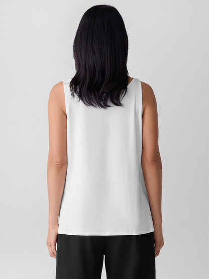 A woman with shoulder-length dark hair is seen from behind, wearing the Eileen Fisher Fine Jersey Scoop Neck Tank in white and black pants against a plain light background.