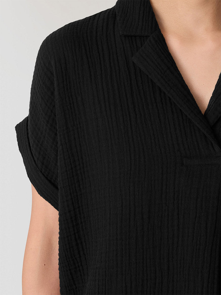 Close-up of a person wearing the Eileen Fisher Organic Cotton Lofty Gauze Notch Collar Top in Black, highlighting the textured fabric, short sleeves, and upper torso.