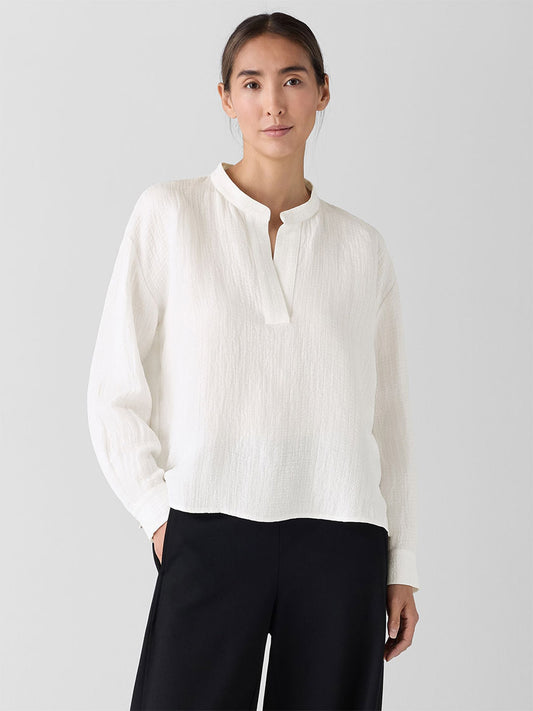 A person wearing the Eileen Fisher Mandarin Collar Top in Ivory and black pants stands against a plain background.