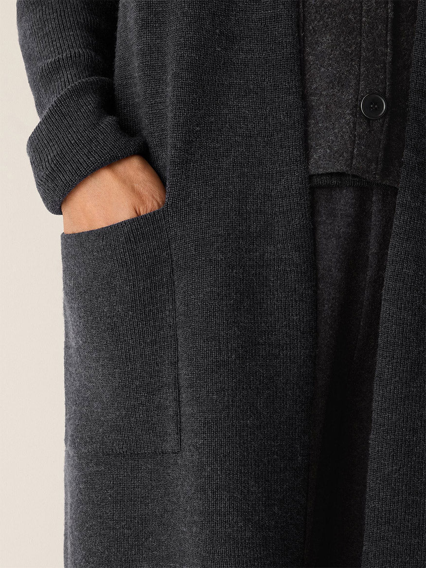 A person wearing the Eileen Fisher Merino Long Cardigan in Charcoal with one hand in a front pocket.
