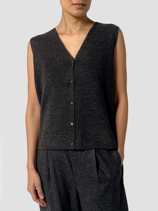 A person wears the Eileen Fisher Merino Wool Vest in charcoal, sleeveless and dark, paired with loose pants, standing against a plain light background.