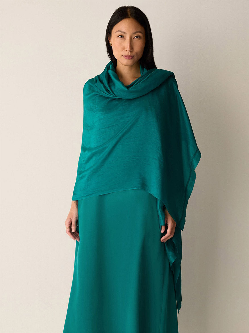 A woman faces forward, draped in the Eileen Fisher Washed Organic Silk Scarf in Teal over a matching dress, set against a plain light background.