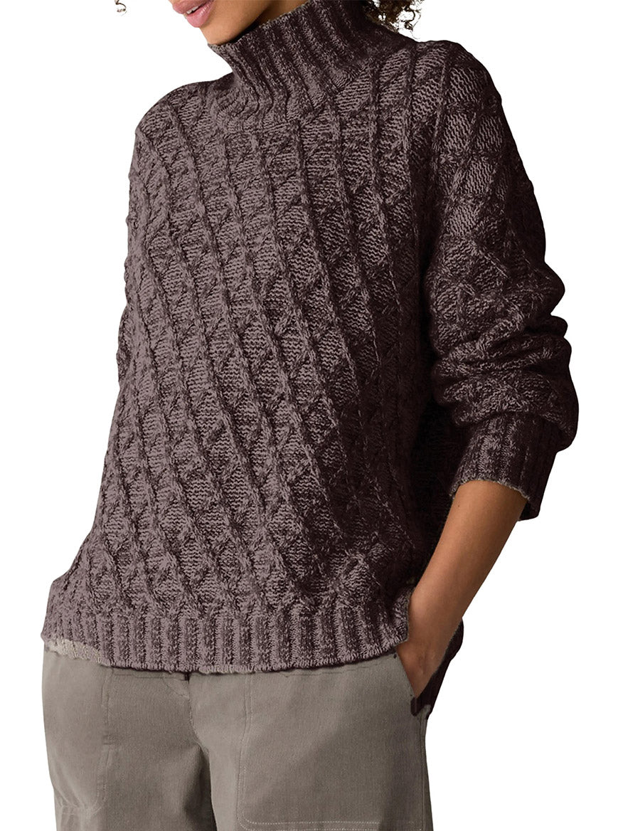 A person wearing a dark brown Eileen Fisher Peruvian Cotton Boucle Fluff Turtleneck in Coffee featuring a diamond cable knit pattern.