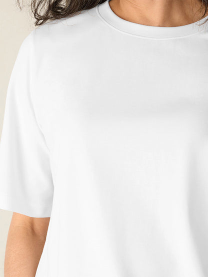 Person wearing the Eileen Fisher Extra-Fine Ponte Crew Neck Tee in White, shown from shoulders to chest with part of the neck and right arm visible.