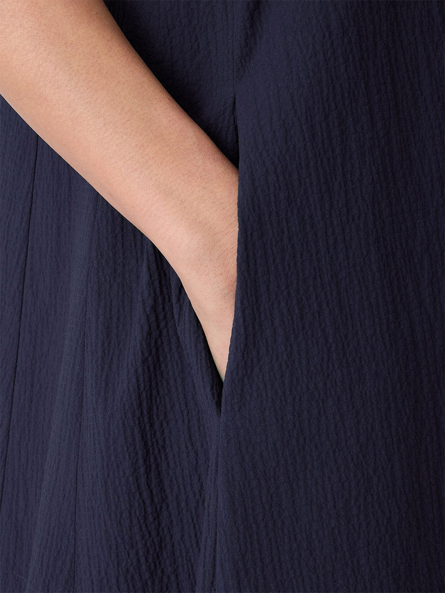 A close-up of a person's hand in the pocket of the Eileen Fisher Organic Cotton Pucker Lantern Dress in Ink, featuring a dark, textured look.