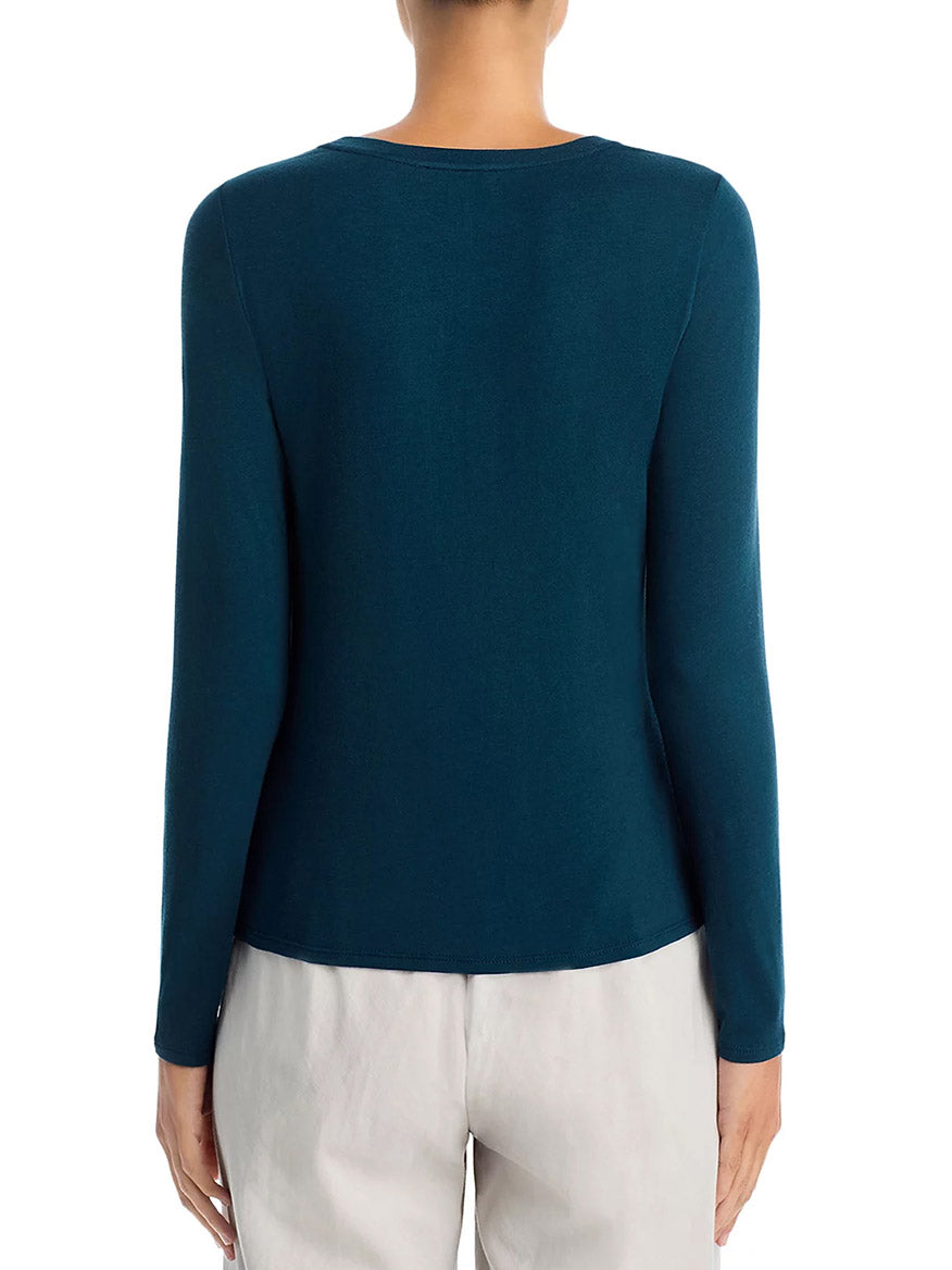 Person wearing the Eileen Fisher Sheer Cotton Blend Knit Round Neck Tee in Alpine, long-sleeved with a boxy fit, and light-colored pants, shown from the back against a plain white background.
