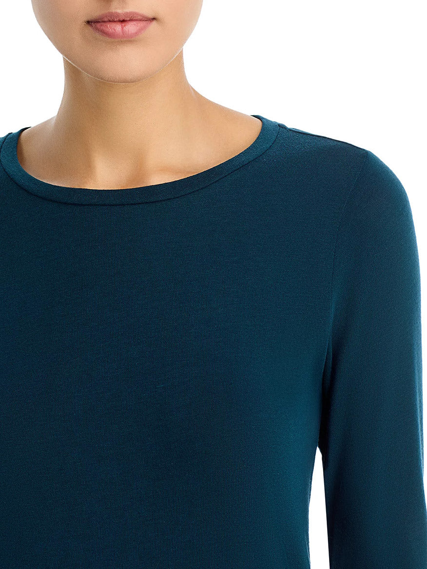 A person is wearing the Eileen Fisher Sheer Cotton Blend Knit Round Neck Tee in Alpine, a long-sleeve, teal top with a boxy fit, shown from the shoulders to just above the lips.