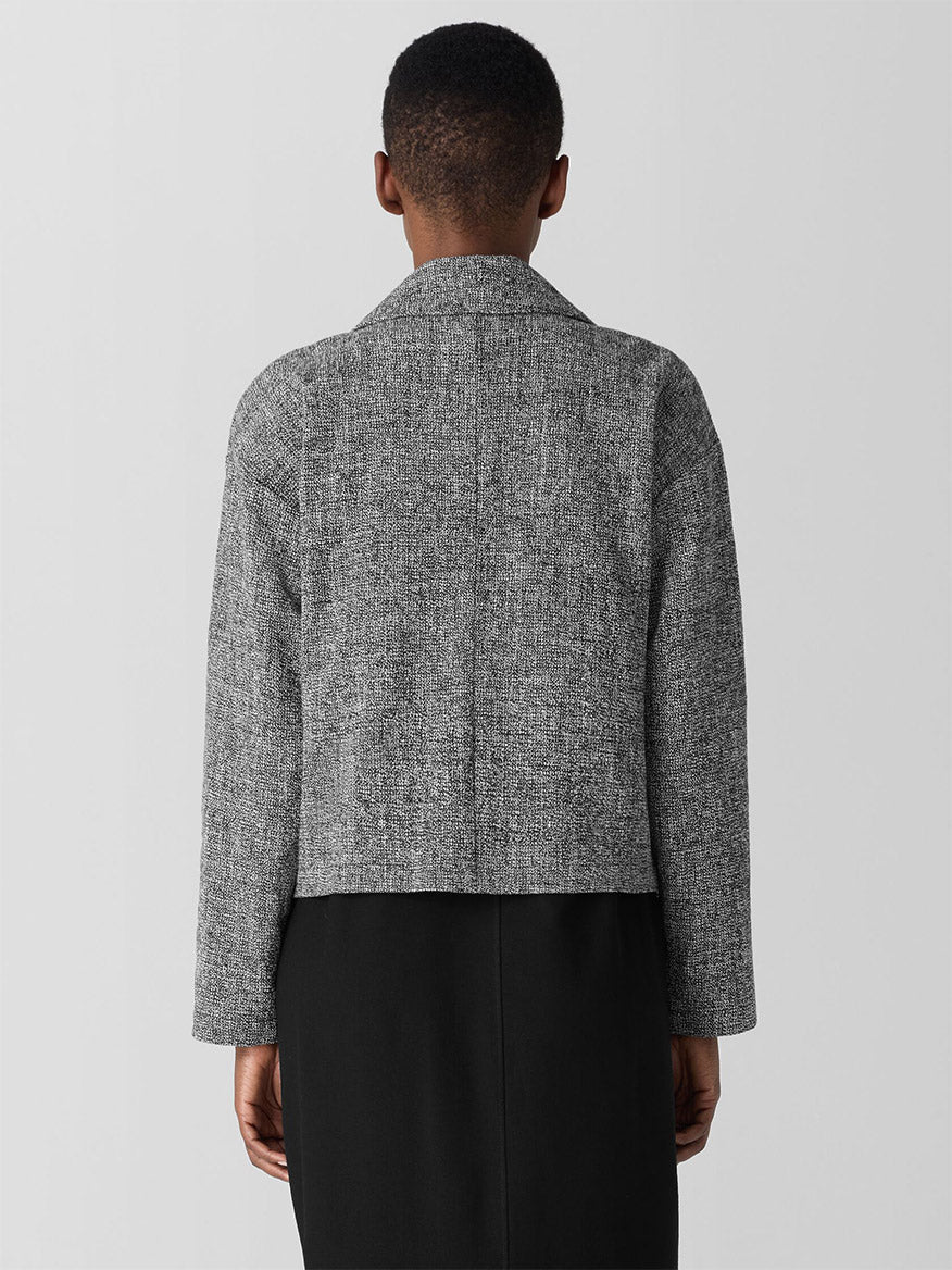 A person faces away, donning the Eileen Fisher Organic Cotton Tweed Short Blazer in Black/White over a black dress against a white background.