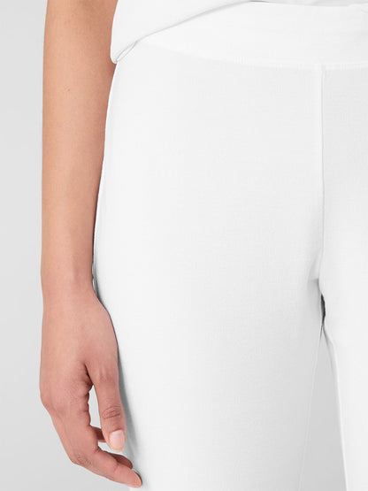 Close-up of a person wearing the Eileen Fisher Washable Stretch Crepe Pant in white, paired with a matching top. The focus is on the left hip and hand, exuding elegance.