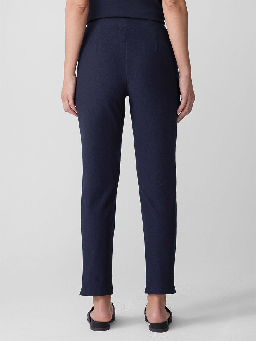 A person is shown from the back wearing Eileen Fisher Washable Stretch Crepe Pant in Ink and black sandals, standing against a plain light gray background.
