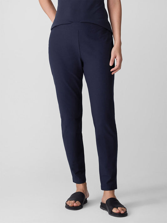 Person wearing the Eileen Fisher Washable Stretch Crepe Pant in Ink, paired with a matching navy top and black slide sandals, standing against a plain light gray background.