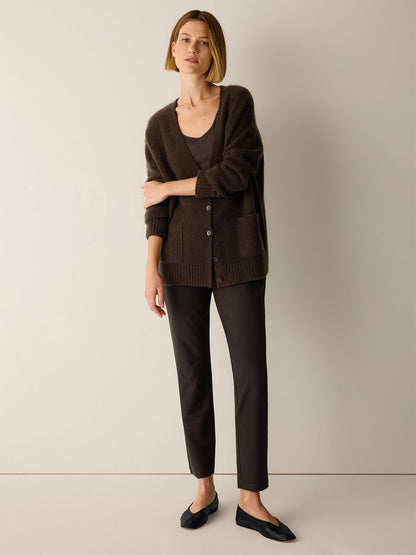 A woman wears a dark brown button-up cardigan over a grey scoop-neck top, paired with Eileen Fisher Washable Stretch Crepe Slim Pant in Coffee and black ballet flats.