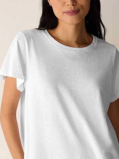 A person wearing the Eileen Fisher Organic Cotton Slubby Jersey Crew Neck Tee in White, shown from shoulders to waist, stands against a neutral background.