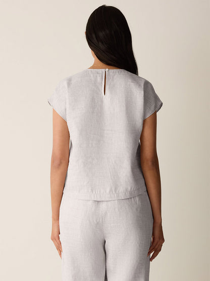 A person stands with their back to the camera, wearing the Eileen Fisher Striped Linen Sheen Square Top in Wheat and matching pants.