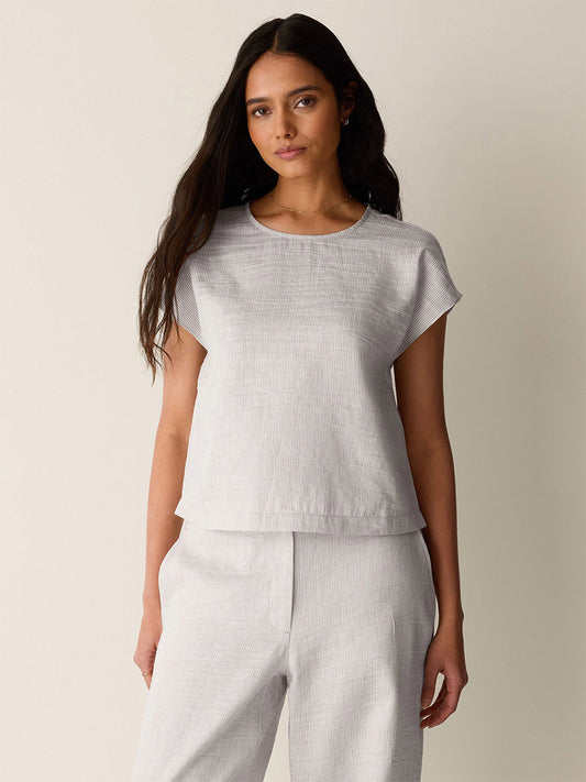 A woman with long dark hair wears the Eileen Fisher Striped Linen Sheen Square Top in Wheat and matching pants, standing against a plain light background.