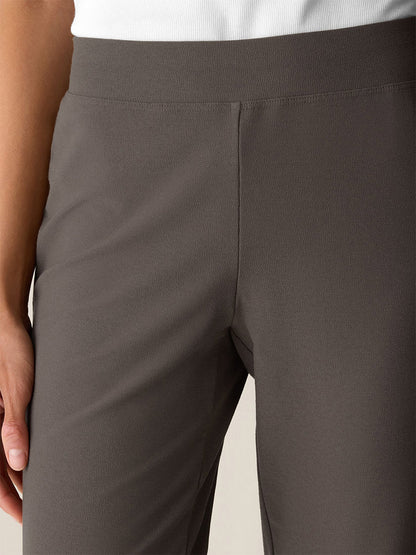 A person wearing the Eileen Fisher Washable Stretch Crepe Slim Pant in Cobblestone and a white shirt, with one hand resting by their side.