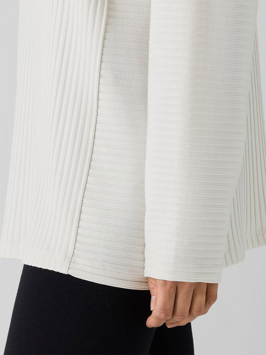 Close-up of someone in Eileen Fisher's Textured Stretch Rib Round Neck Long-Sleeve Top in Bone with black pants, highlighting the ribbed texture and detail.