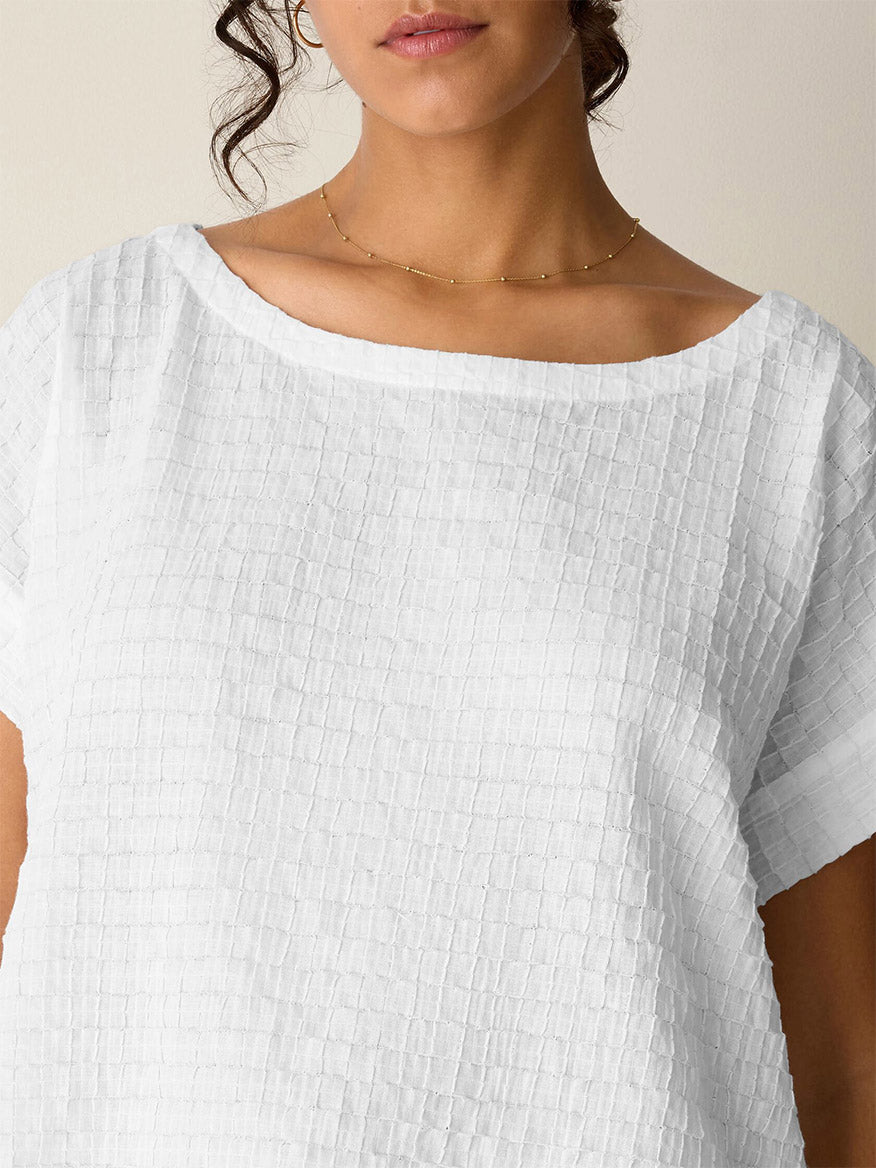 A woman wears the Eileen Fisher Organic Cotton Voile Box Square Top in White and a delicate gold necklace, shown from the shoulders up.