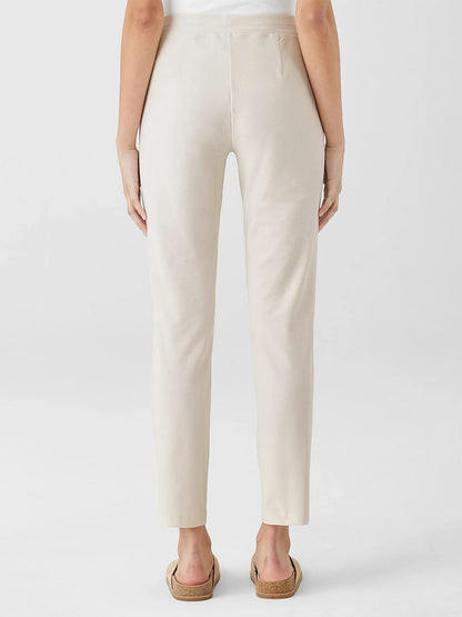 Person wearing Eileen Fisher Washable Stretch Crepe Pant in Bone and sandals, standing with their back to the camera against a plain background.