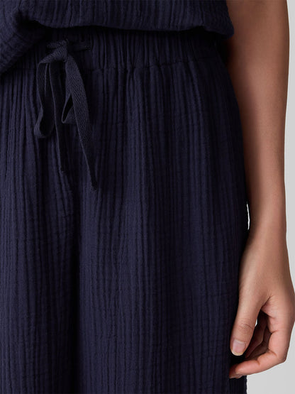 Close-up of a person wearing Eileen Fisher Organic Cotton Lofty Gauze Wide-Leg Pant in Ink, featuring a drawstring waist and crafted from soft organic cotton, with their right hand resting by their side.