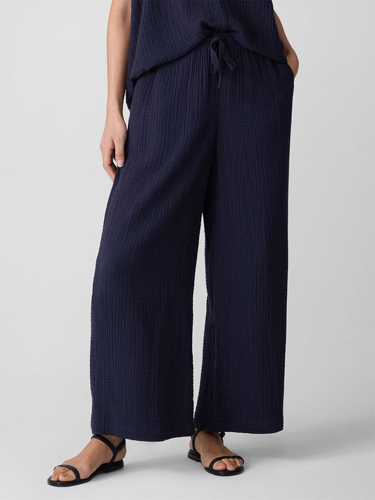 Someone stands against a plain light background wearing the Eileen Fisher Organic Cotton Lofty Gauze Wide-Leg Pant in Ink with a matching top and black sandals.