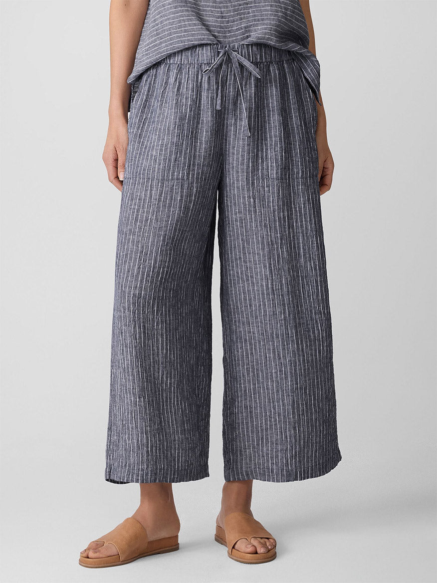 Person wearing Eileen Fisher Puckered Organic Linen Wide-Leg Pant in Black/White with a drawstring waist. Features gray and white stripes, loose fit, Fair Trade Certified. Paired with brown flat sandals; upper body partially out of frame.