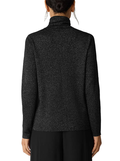 A person is seen from behind wearing the Eileen Fisher Wool Lurex Turtleneck Sweater in Black, featuring subtle metallic shimmer, paired with black pants.