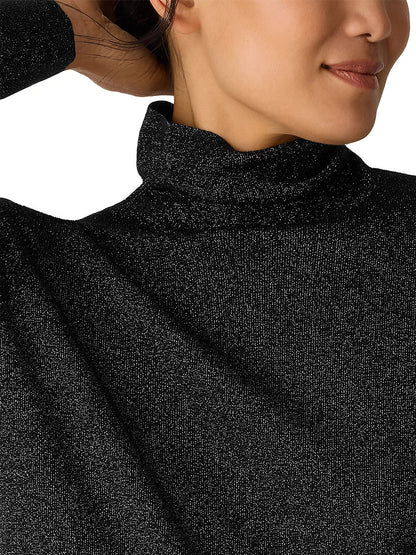 Close-up of a woman in the Eileen Fisher Wool Lurex Turtleneck Sweater in Black, featuring metallic fibers, her face partially visible and left arm raised.