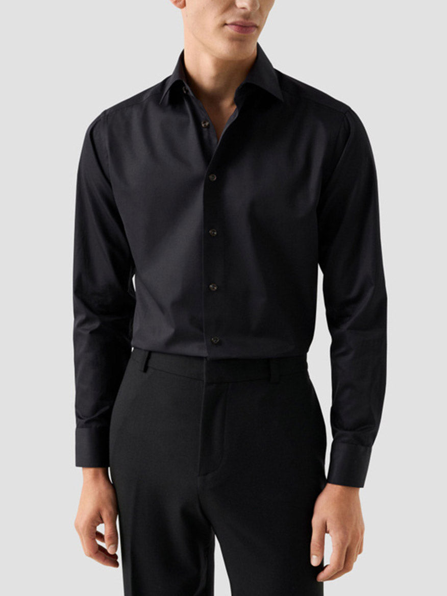 A man wearing an Eton Contemporary Fit Solid Elevated Twill Dress Shirt in black organic Supima cotton, tucked into black trousers.