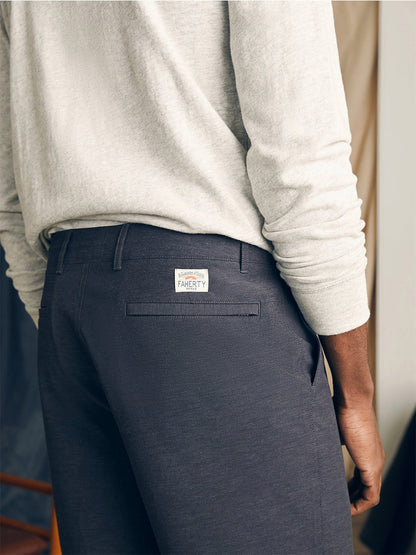 Close-up of a person wearing gray Faherty Brand All Day Shorts in Charcoal with a back pocket featuring a "faherty" brand label.