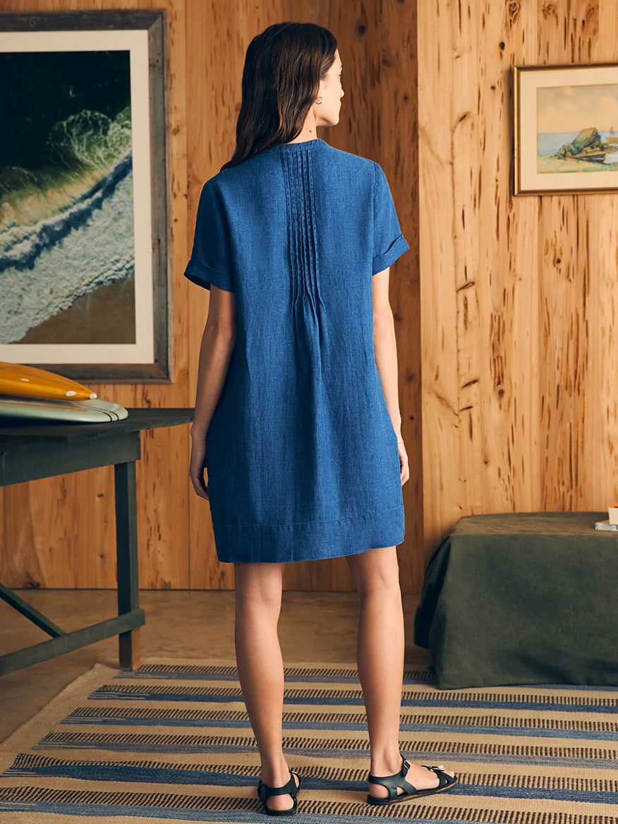 Woman in a Faherty Brand Gemina Basketweave Dress in Indigo standing in a wood-paneled room.