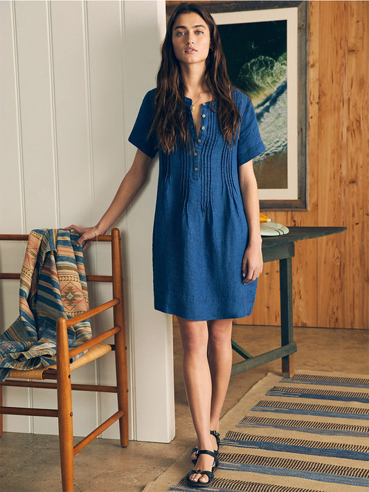 Woman standing in a wooden room wearing a Faherty Brand Gemina Basketweave Dress in Indigo and black sandals.