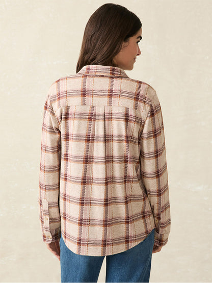 A person with long, dark hair is seen from behind, wearing the ultimate in-between seasons shirt – the Faherty Brand Legend Sweater Shirt in Cranberry Haze, paired with blue jeans against a neutral background.