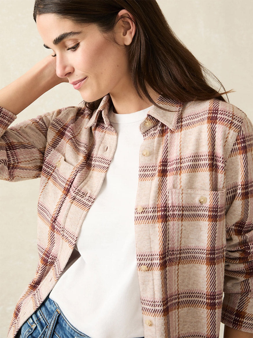 A person with long brown hair wearing the Faherty Brand Legend Sweater Shirt in Cranberry Haze, the ultimate in-between seasons shirt, stands against a plain background with a relaxed expression.