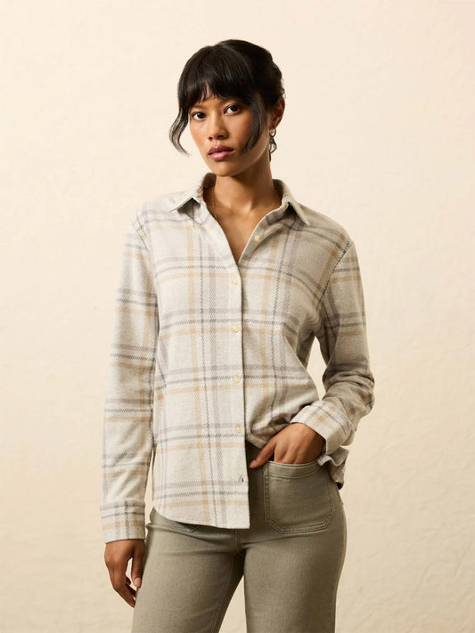A woman wears the Faherty Brand Legend™ Classic Sweater Shirt in Sandy Trails Plaid with light gray pants, standing against a plain, light background.