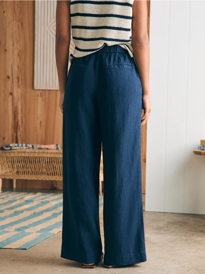 Rear view of a person wearing Faherty Brand Monterey Linen Pant in After Midnight and a striped top, standing in a wooden-paneled room.