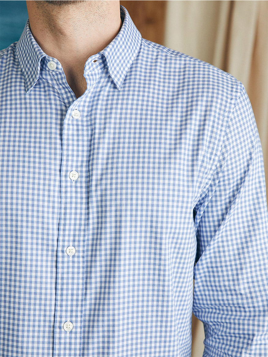 A person wearing a Faherty Brand Movement Shirt in Light Blue Gingham, made with wrinkle-resistant Supima cotton, visible from the chest up.