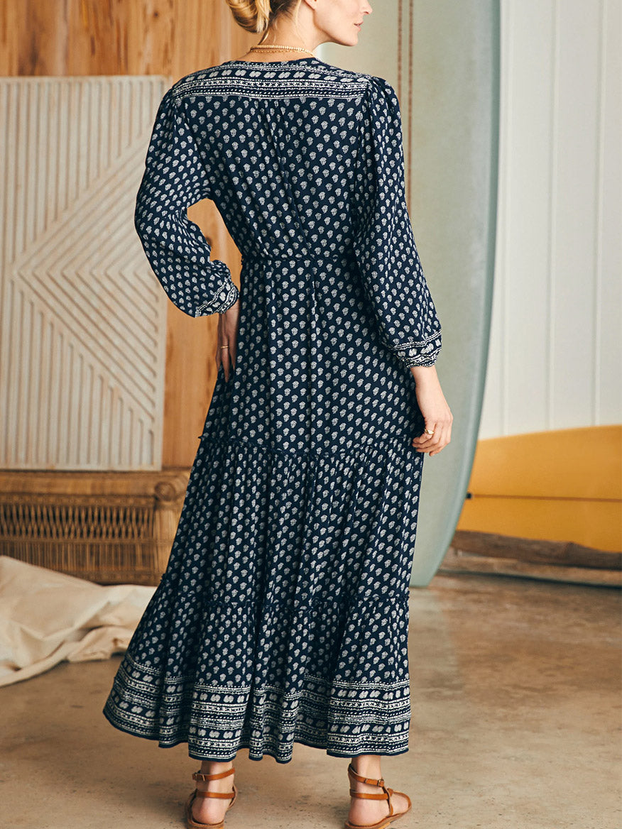 A woman standing with her back to the camera, wearing the Faherty Brand Orinda Long Sleeve Maxi Dress in Lotus Floral Print.