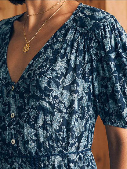 Close-up of a person wearing a Faherty Brand Orinda Maxi Dress in Blue Esna Floral with puff sleeves and a leaf pendant necklace.