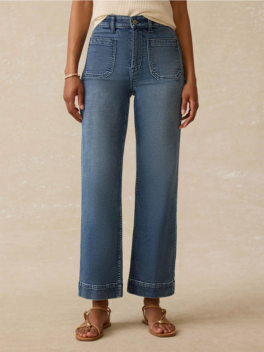 Wearing Faherty Brand Stretch Terry 5-Pocket Ankle Pant in Riverton, a sleeveless relaxed-fit ribbed top, sandals, and a bracelet, a person stands against a plain background.