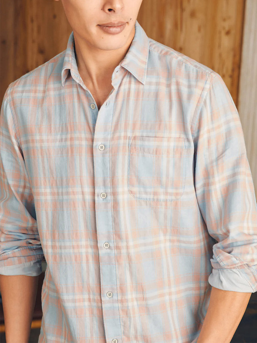 Person wearing a Faherty Brand Sunwashed Chambray Shirt in Coral Bay Plaid with rolled-up sleeves.
