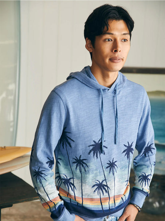 Man in a Faherty Brand Sunwashed Slub Hoodie in Palm Rainbow Ombre, crafted from American-grown cotton, standing indoors.