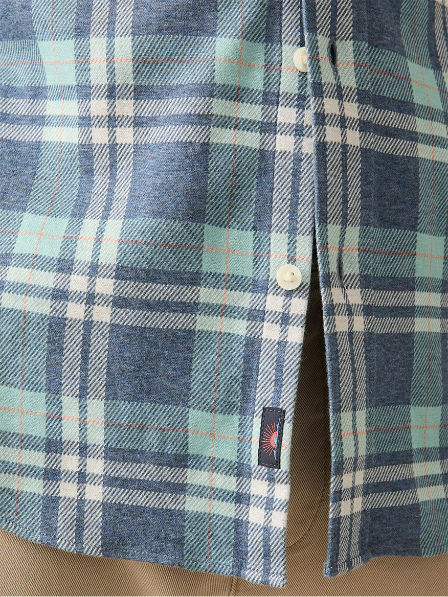 Close-up of the Faherty Brand Coastline Knit Shirt in Holbrook Island Plaid, featuring a blue and green plaid design with white buttons for comfort and wearability. A small black tag is sewn near the bottom hem.