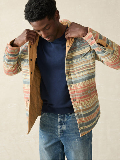 A man adjusting his Faherty Brand Doug Good Feather Reversible Bondi Jacket in Dried Palm Eldorado Springs over a navy shirt and jeans.