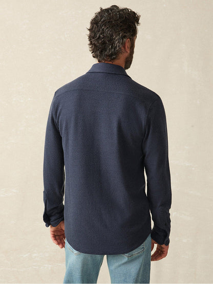 A person with curly hair is seen from the back against a plain background, wearing the bestselling Faherty Brand Legend Sweater Shirt in Brighton Navy Twill and jeans, showcasing a cozy texture.