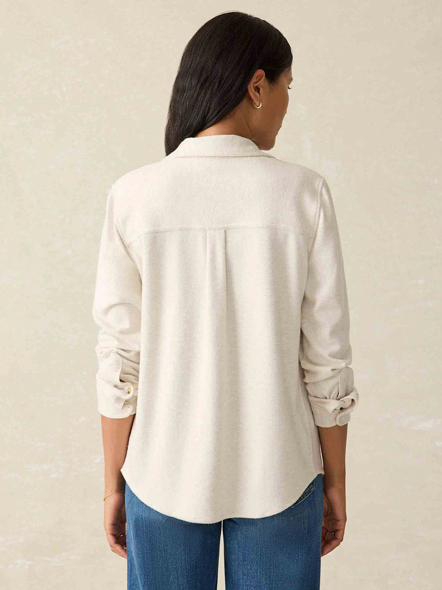 A woman with long dark hair is wearing a Faherty Brand Legend Sweater Shirt in Off White, paired with blue jeans, seen from the back.