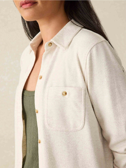 A close-up showcases a person wearing the Faherty Brand Legend Sweater Shirt in Off White, featuring a cream-colored button-up design over a green top. Its custom fabric blend offers comfort and elegance, perfect for any occasion.