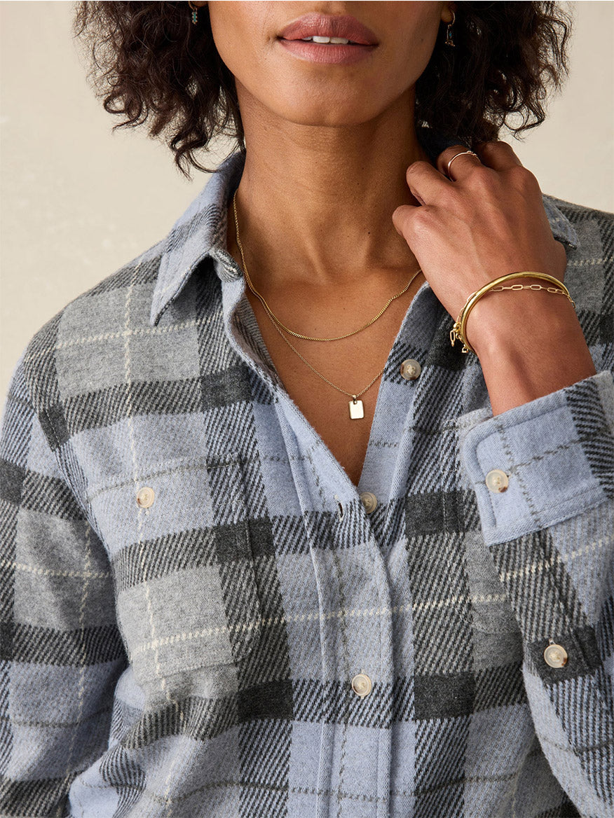 A person wearing a popular Faherty Brand Legend Sweater Shirt in True North Plaid, layered necklaces, and a bracelet.