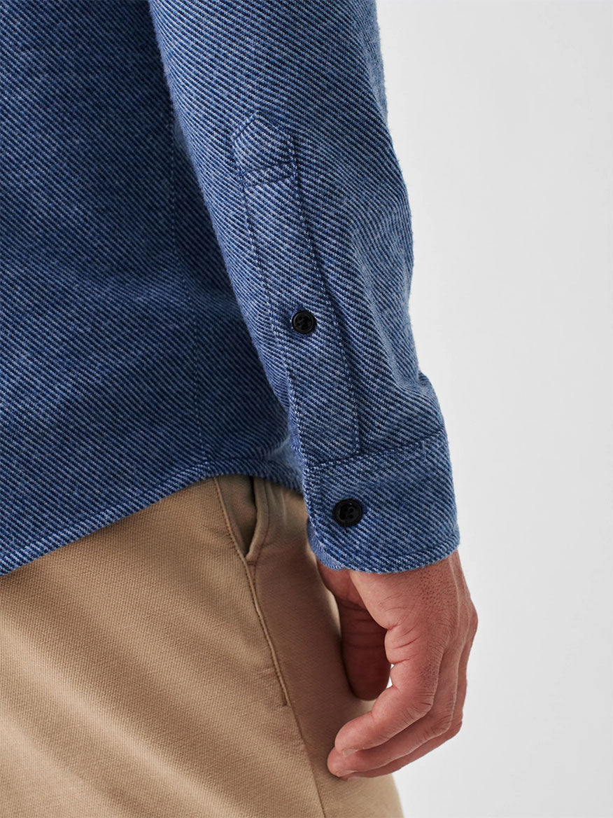 Close-up of a person wearing the Faherty Brand Legend Sweater Shirt in Glacier Blue Twill, featuring buttoned cuffs and perfect as a versatile layering piece, paired with beige pants.